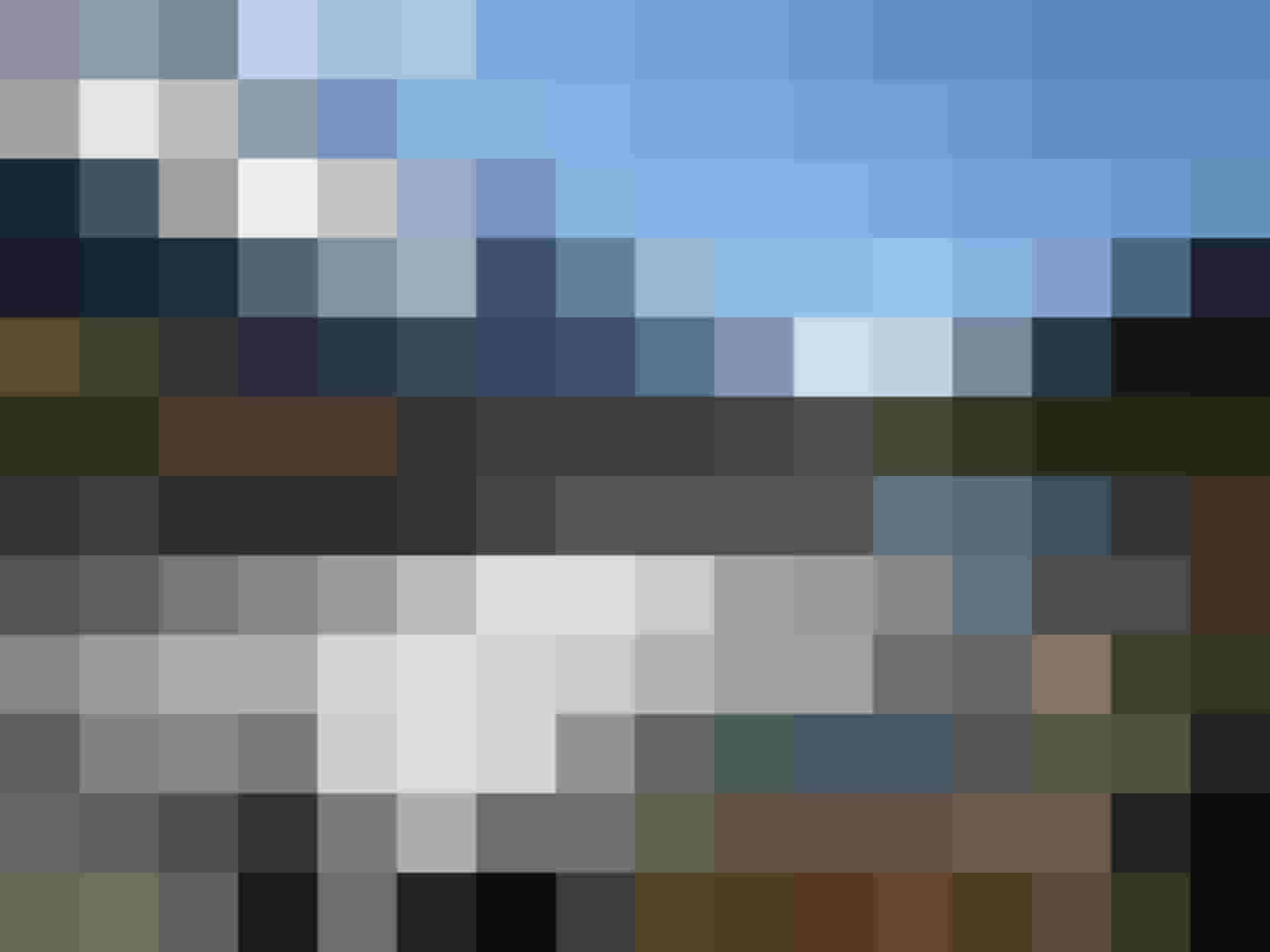 Klarer Gebirgsbach mit Steinen im Sonnenschein vor alpiner Bergkulisse