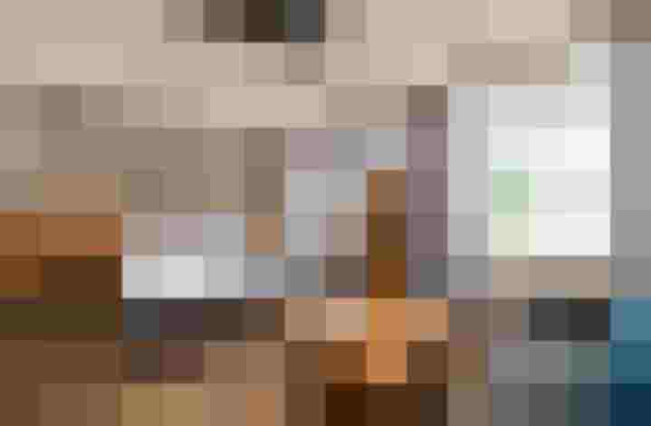 Modernes Hotelzimmer mit Doppelbett, Holzmöbeln, Sofa und Blick auf grüne Berge