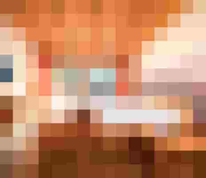 Helles Hotelzimmer mit Holzmöbeln, Doppelbett, Sofa und Balkonblick auf die Alpen